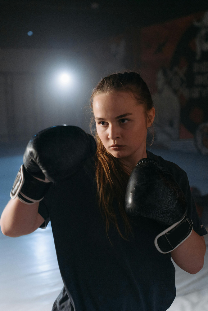 A young girl in Denver wearing boxing gear uses a sports mouthguard to protect her smile