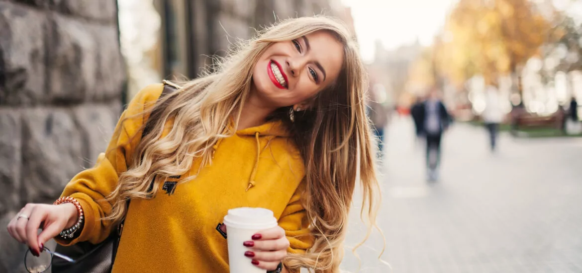young woman in a yellow sweater smiling, showing off her cosmetic dental work in Denver