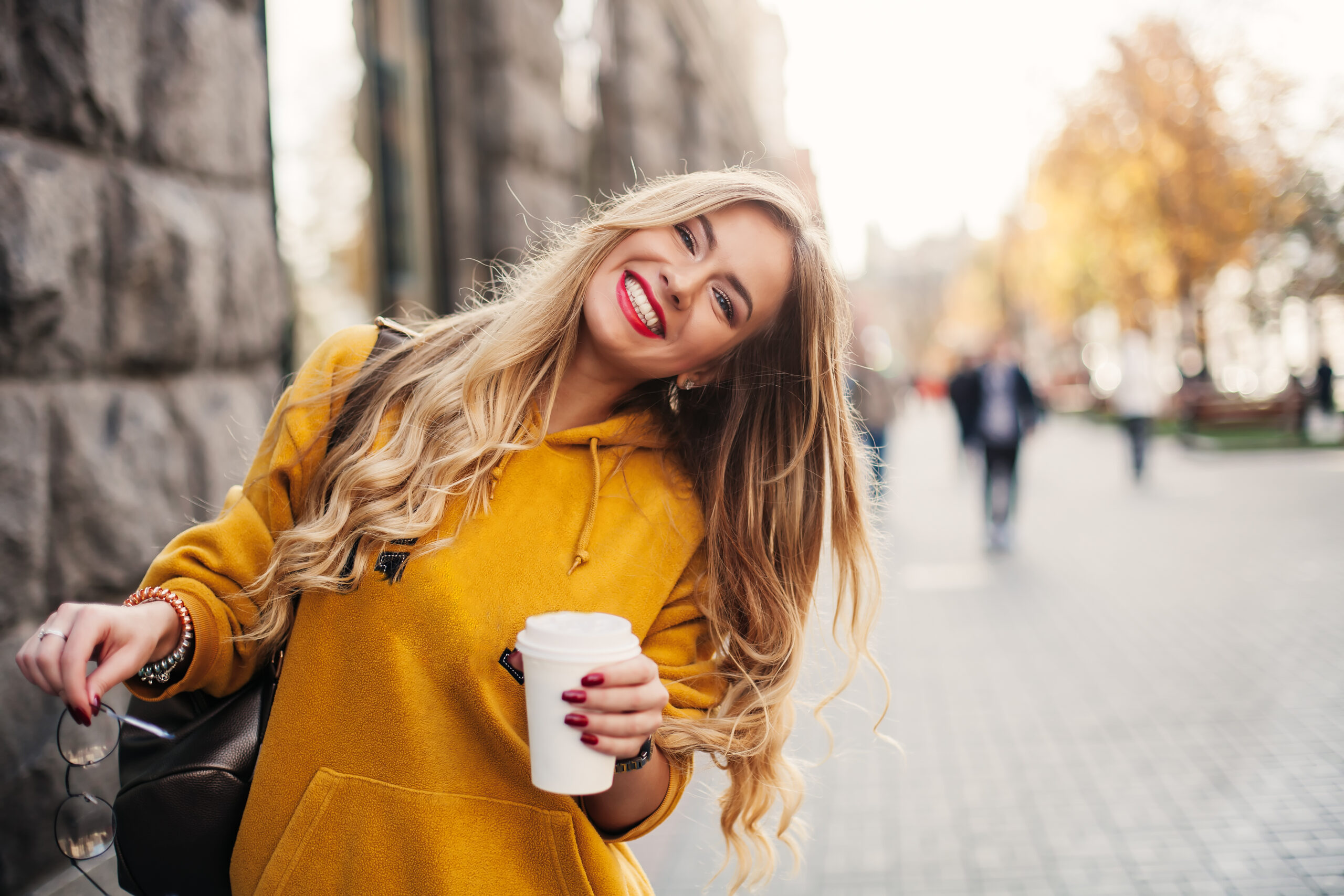 young woman in a yellow sweater smiling, showing off her cosmetic dental work in Denver