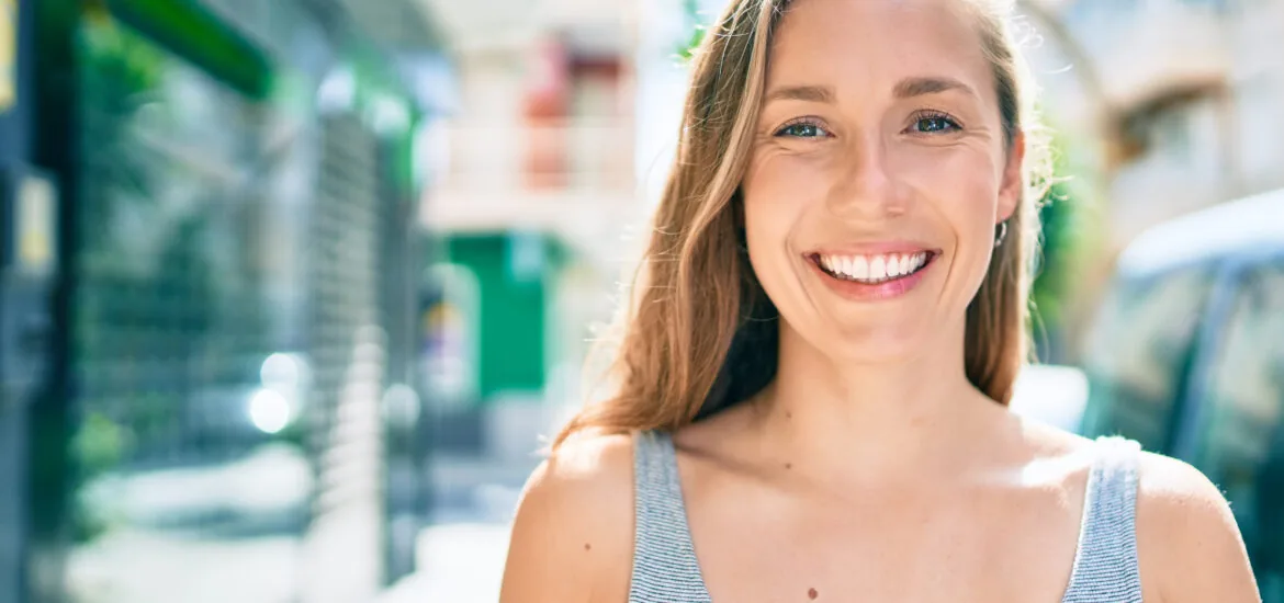 smiling young woman on a city street, perfect white smile