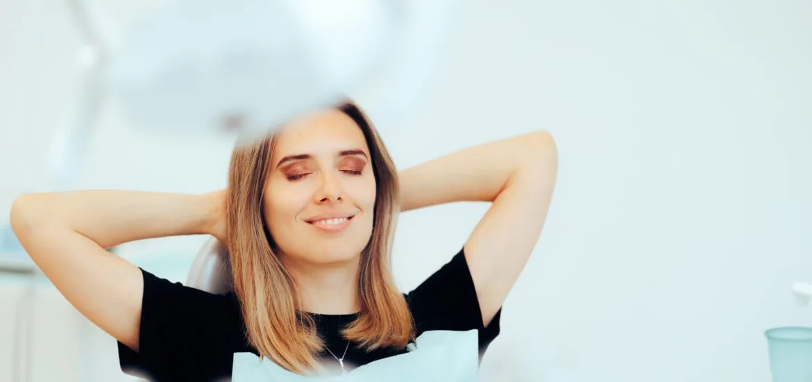 Happy Relaxed Patient Sitting in a Dental office. Carefree woman happy with the results after dental treatment