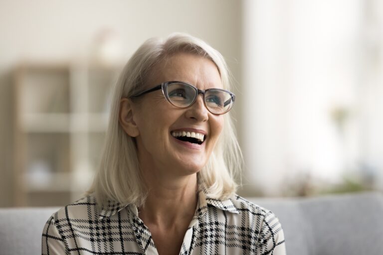 mature woman smiling on a couch, new dental implant