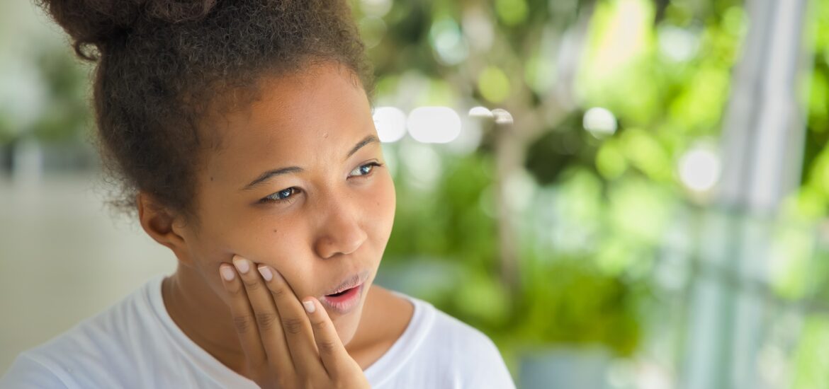 young woman holding her jaw, severe wisdom teeth pain