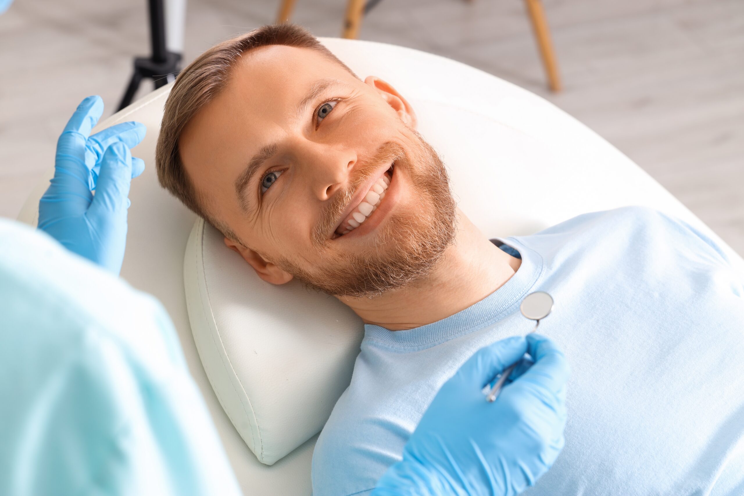 Smiling young man visiting dentist on couch in clinic, closeup