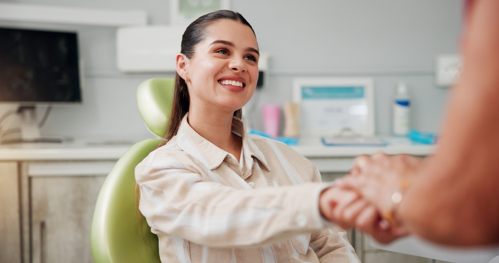 young woman shaking hands with a dental professional in a modern dental office